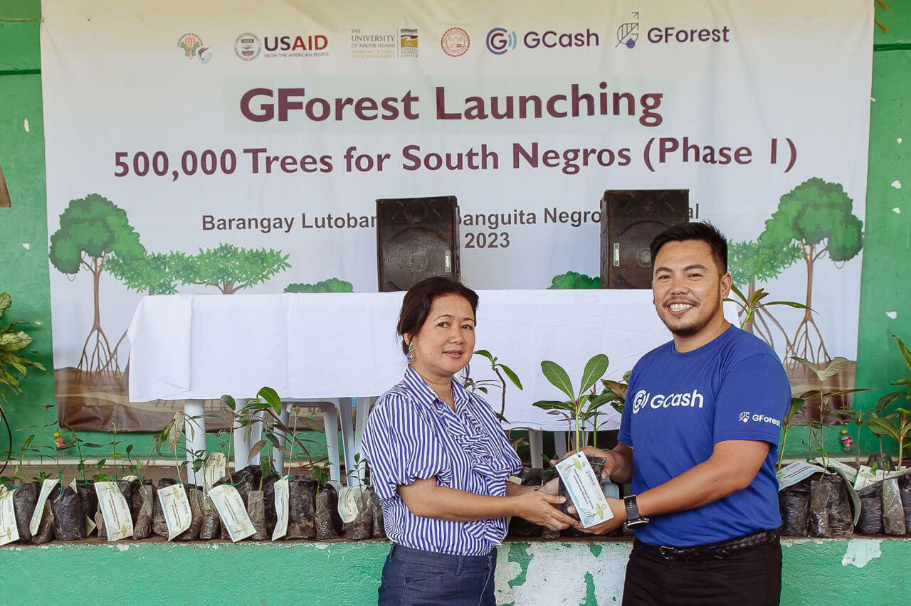 Mayor Peve Ligan of Sta. Catalina receives the reforestation kits handed by GCash Head for Sustainability CJ Alegre. Sta. Catalina is among the five towns that will participate in this initiative.