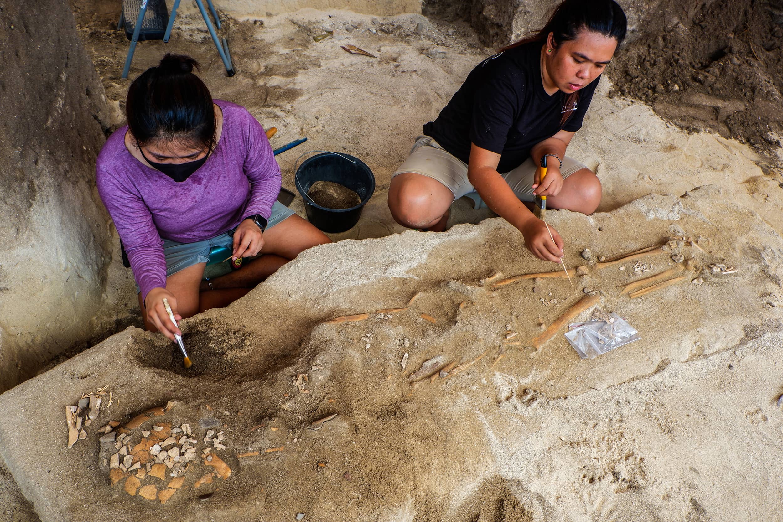 AT THE BEACH. Graduate students Candice Theara Cañete (left) and Maria Cecilia Cabañes work to expose the skeleton uncovered at the Lapyahan public beach. The skeleton had a dagger-like tool buried with it. (Photo by Max Limpag)
